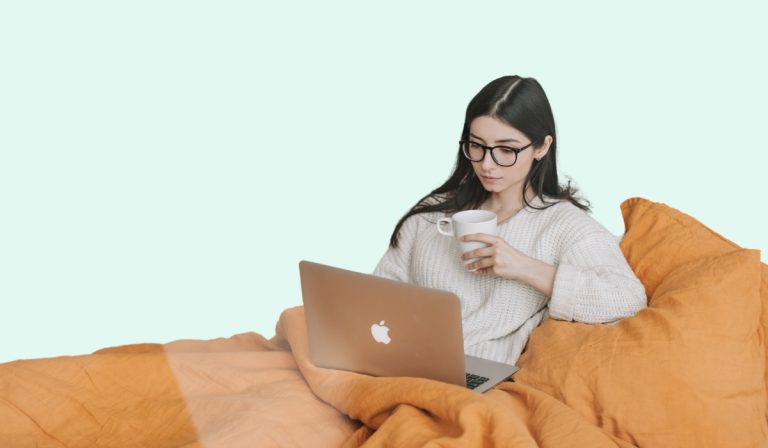 woman sits in bed, studying from home