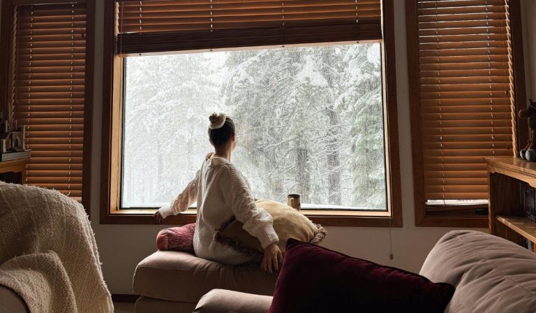 woman looks out cabin window Canada in December Fun Things to Do in Canada in Winter
