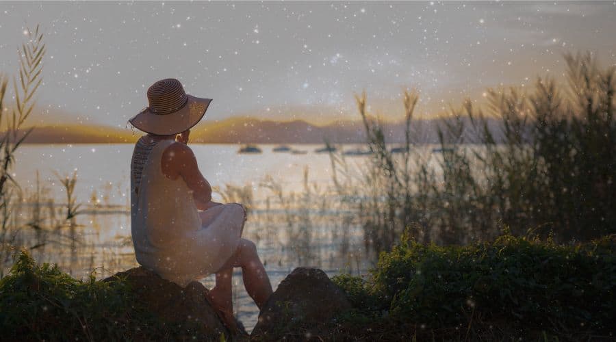 Woman sitting by lake, wondering how long a spiritual awakening lasts