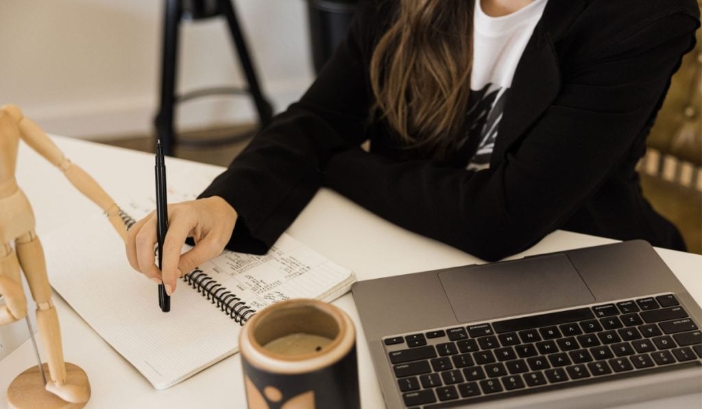 womn writes in her journal using New Month Journal Prompts to start the month right