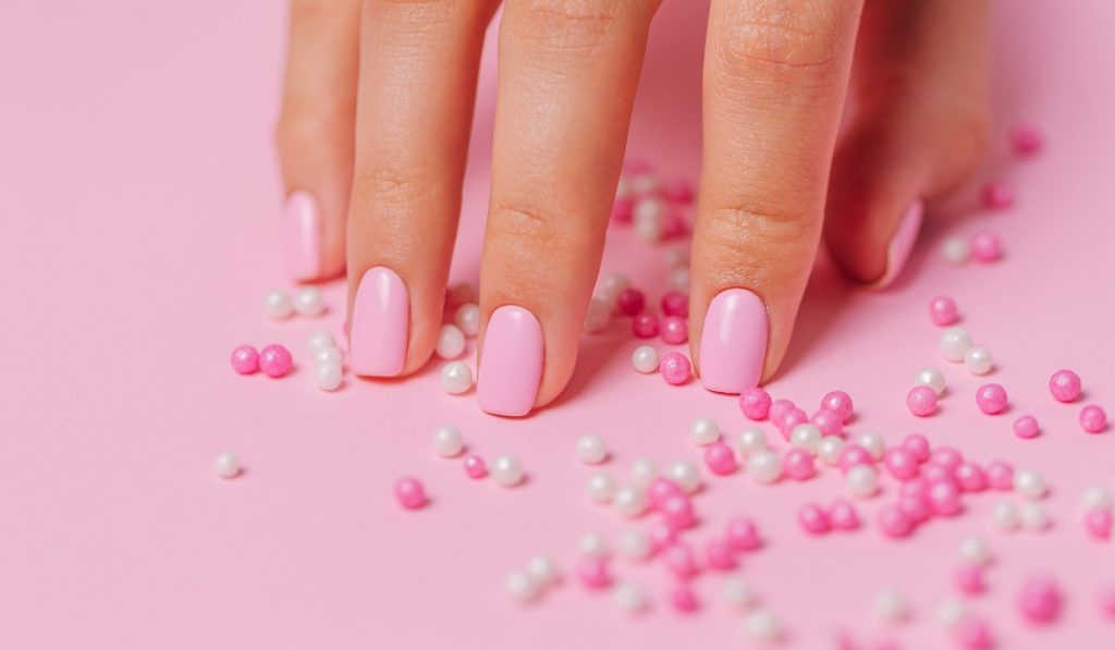 hand with bubblegum-pink nails sowing example of fun colorful graduation nails ideas